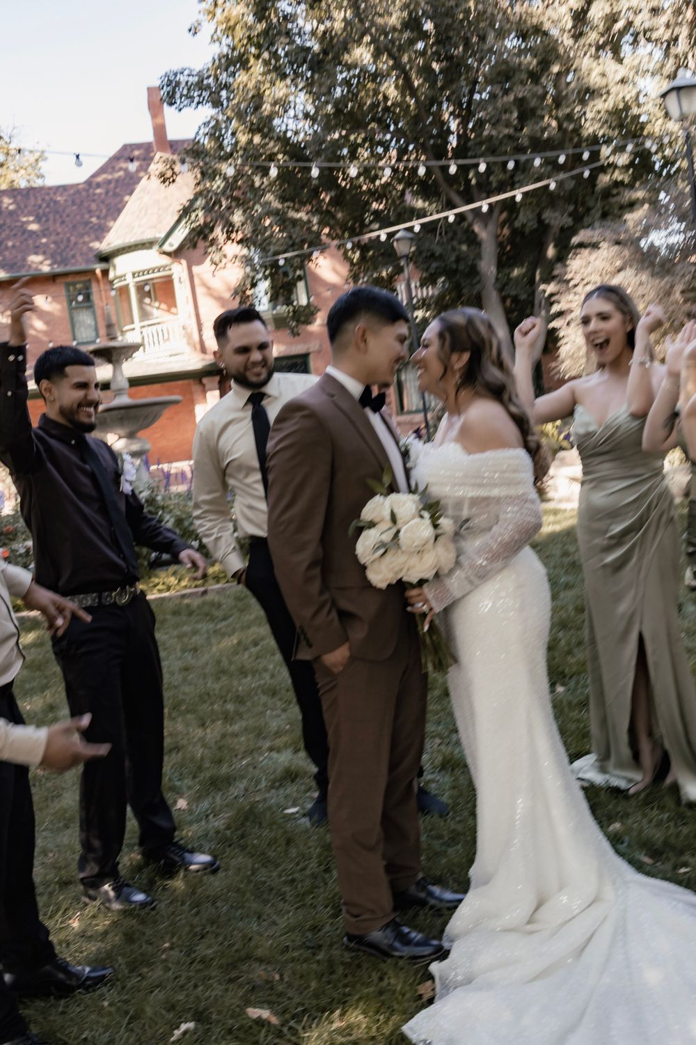 Bride and Groom smile at each other with the wedding party around them