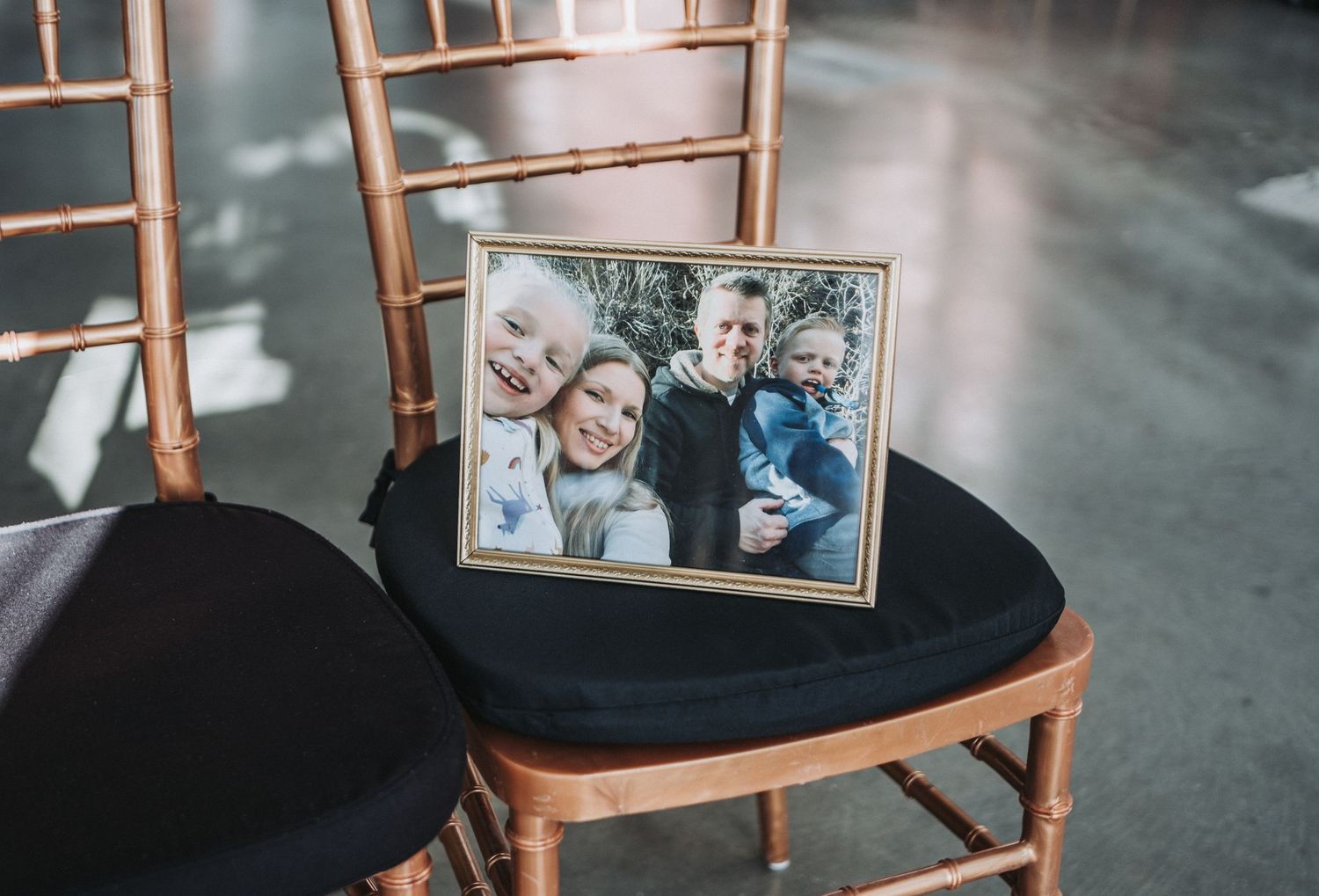 A framed photograph displayed on a wooden Chiavari chair at a wedding venue.