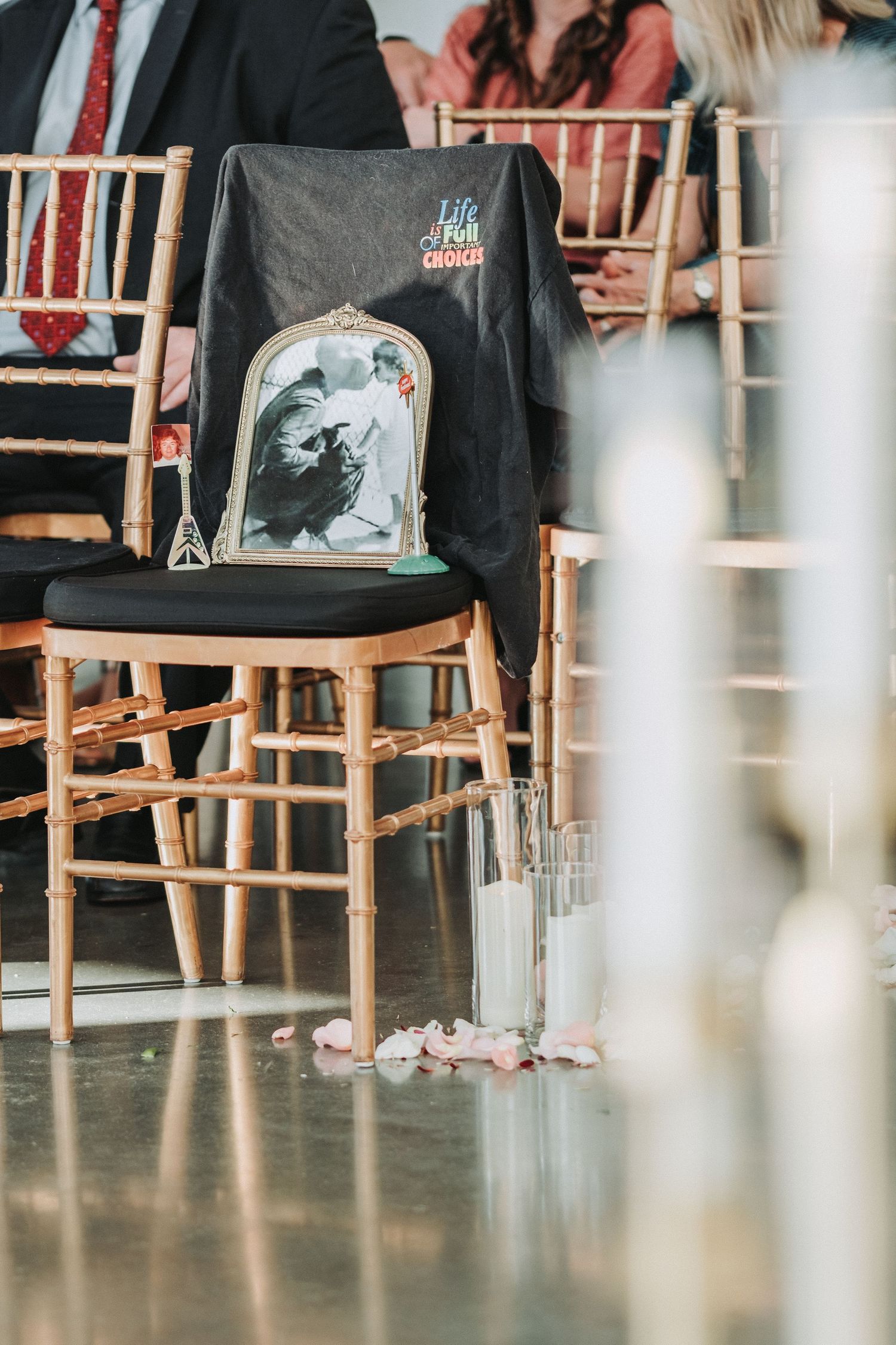 A black t-shirt with gothic design draped over a wooden chiavari chair at a wedding venue.