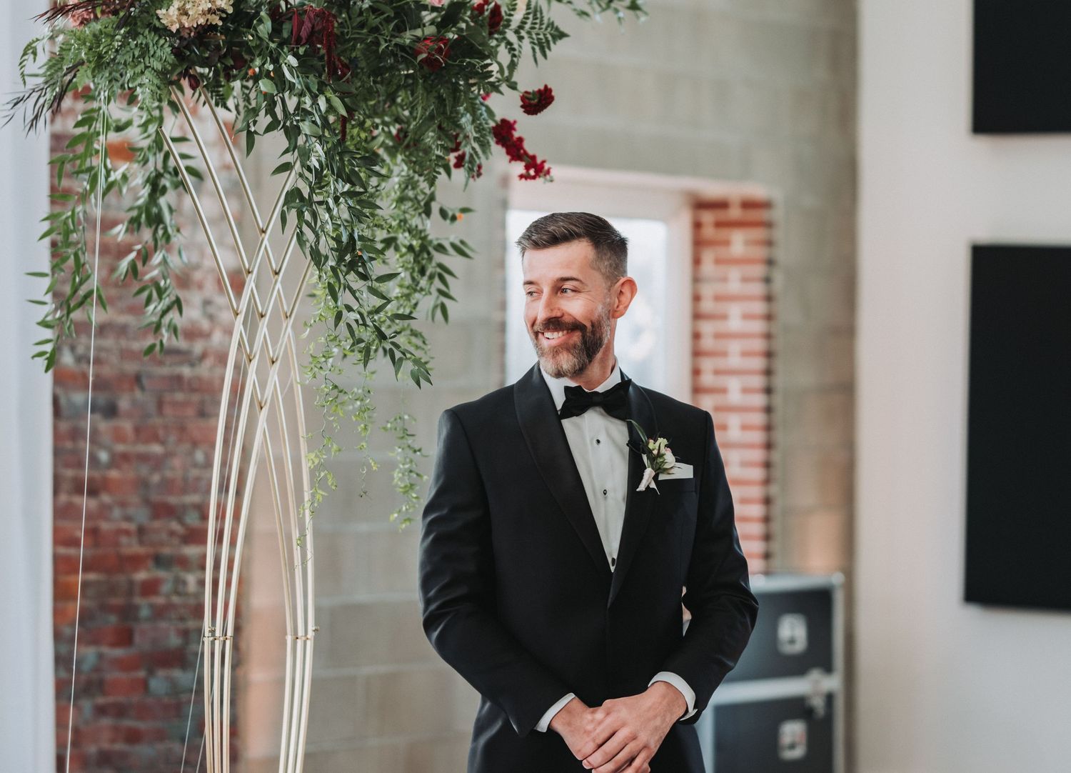A formal wedding ceremony setting with elegant floral arrangements and exposed brick walls.