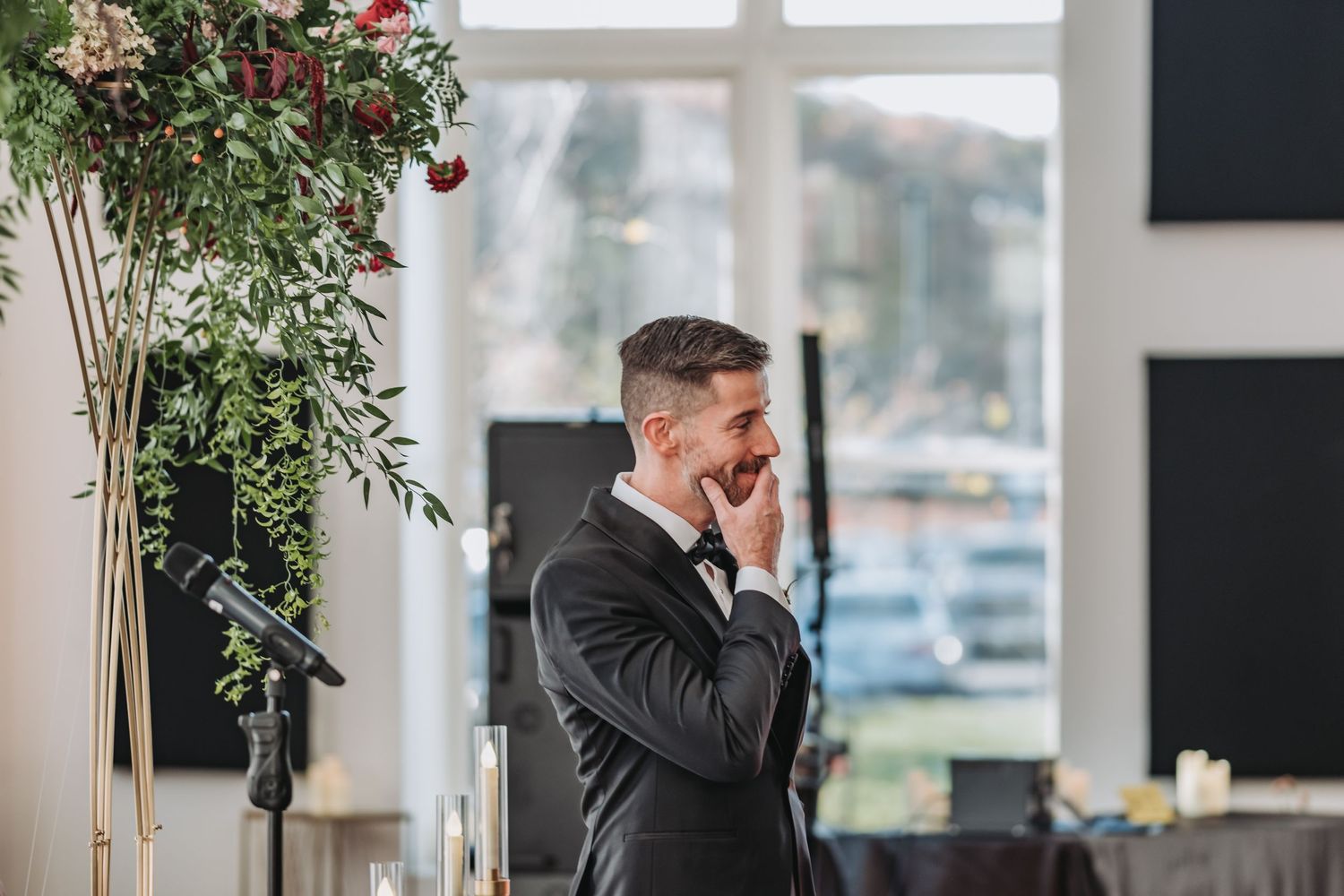 Emotional groom in black suit wipes tears during wedding ceremony.