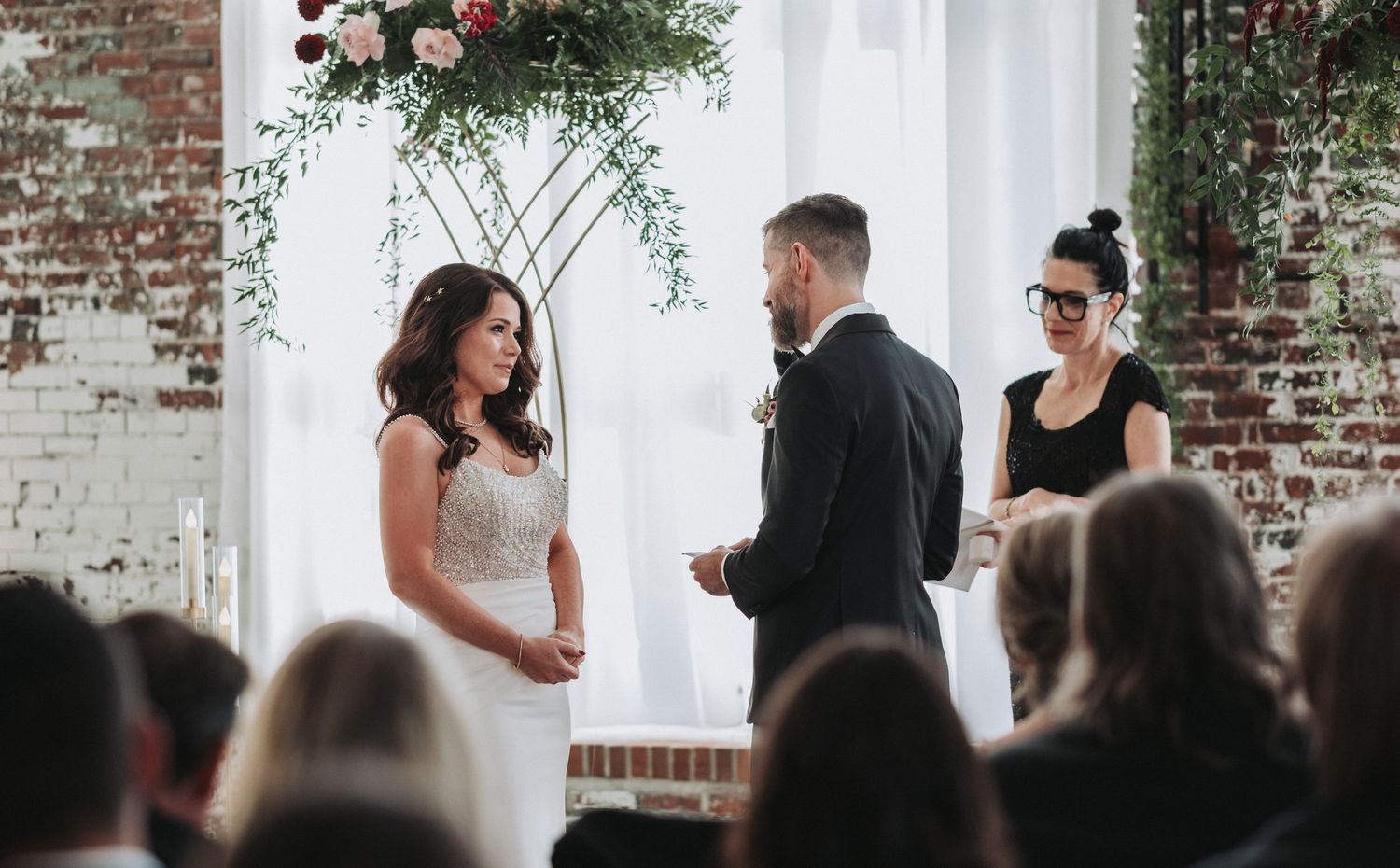 A wedding ceremony in progress inside an industrial-style venue with exposed brick walls.