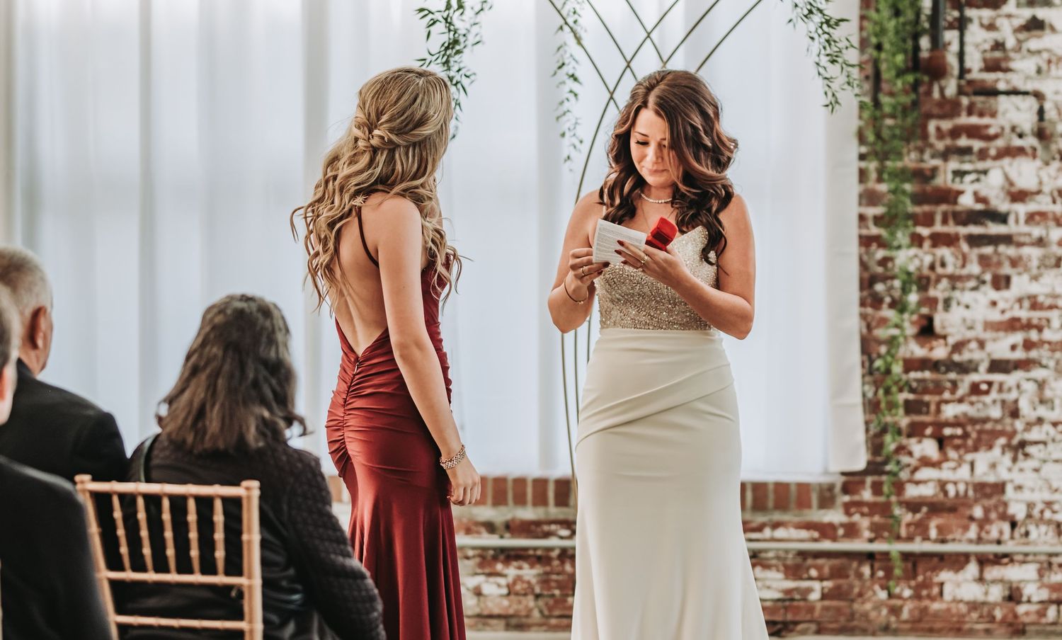 An elegant indoor wedding ceremony with a person in white dress speaking at the altar.