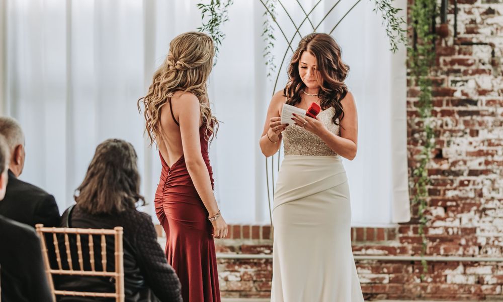 An elegant indoor wedding ceremony with a person in white dress speaking at the altar.