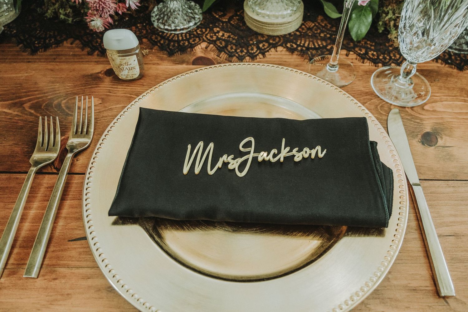Black napkin with 'Mr Jackson' calligraphy on white plate with silverware and greenery.