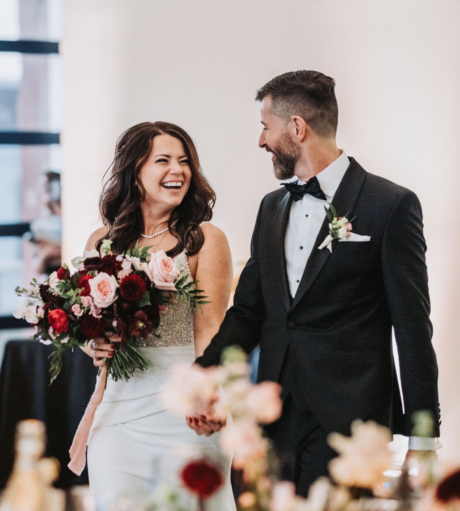 Couple sharing a joyful moment with bouquet at their wedding celebration.