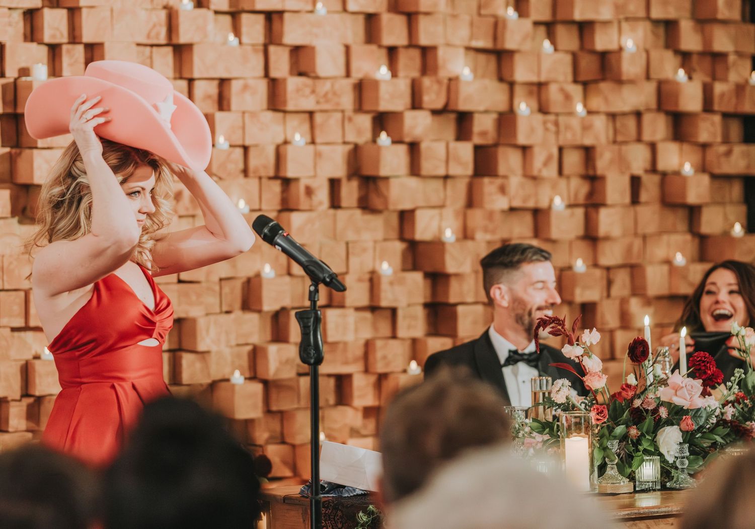 Wedding reception speech causing laughter among guests at modern venue.