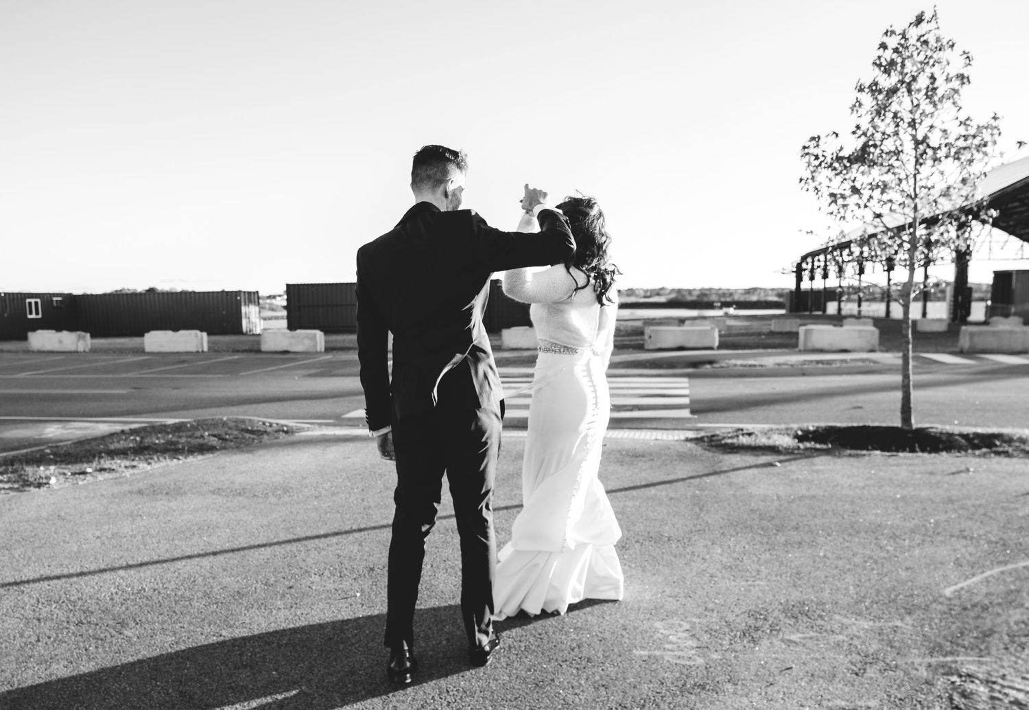 Black and white portrait of couple walking away on empty parking lot.