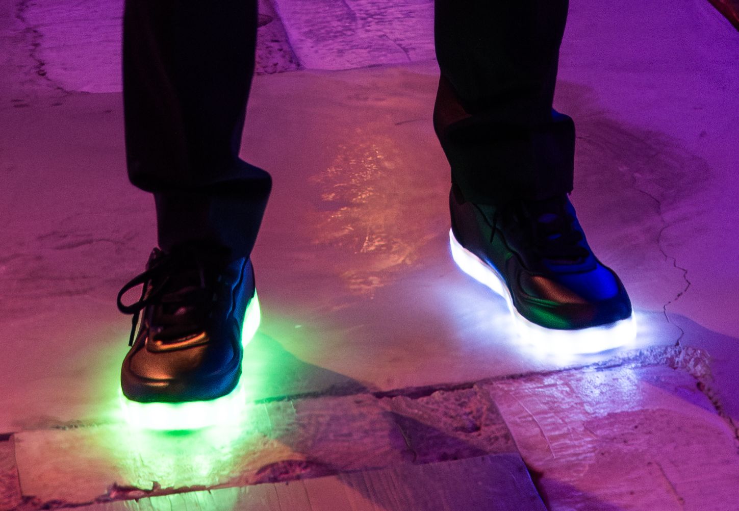 Light-up shoes glowing on dance floor with purple lighting effects.