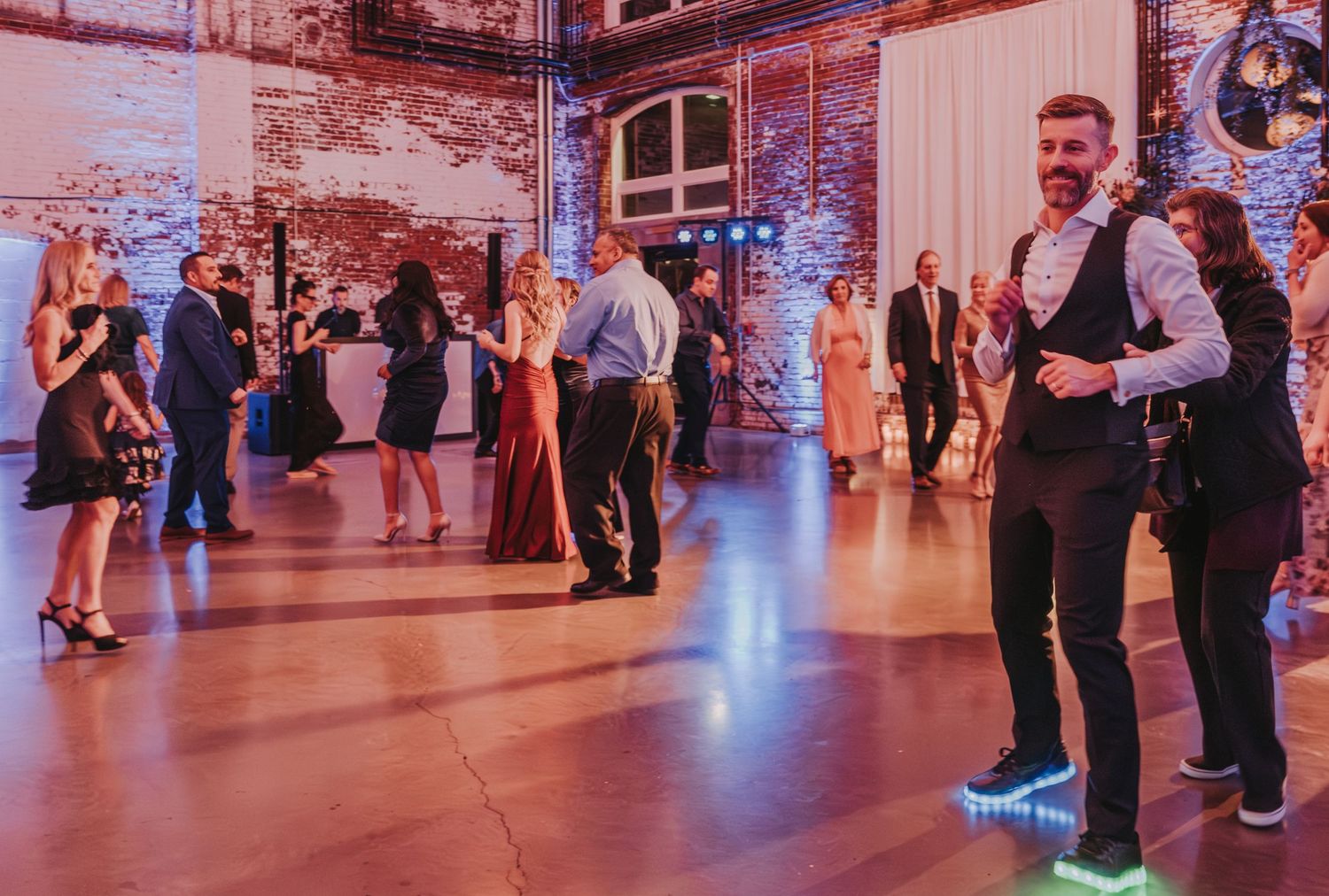 Guests dancing at wedding reception at Halo at the Point in Portland, Maine in a rustic brick venue with ambient lighting.