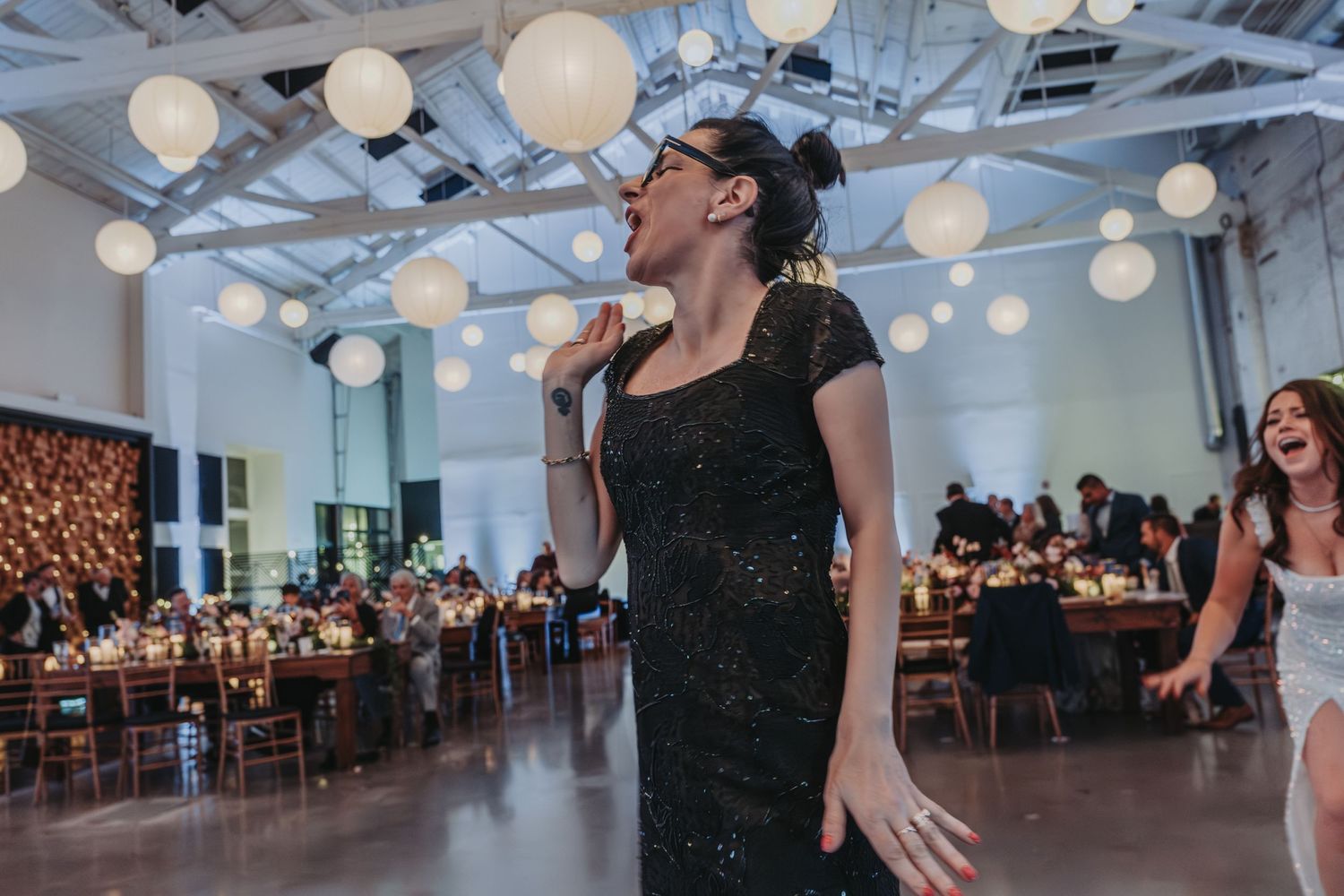 Singer performs passionately at wedding reception venue decorated with hanging paper lanterns.
