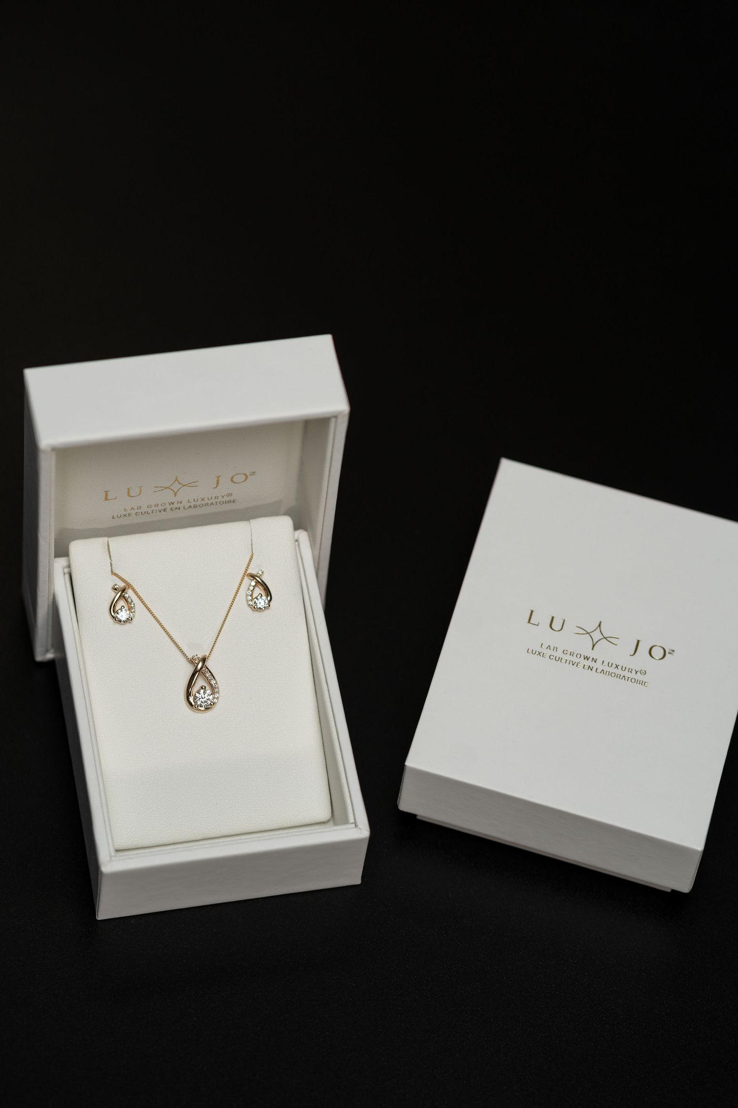 Open jewelry boxes showing necklaces and earrings with branded packaging.