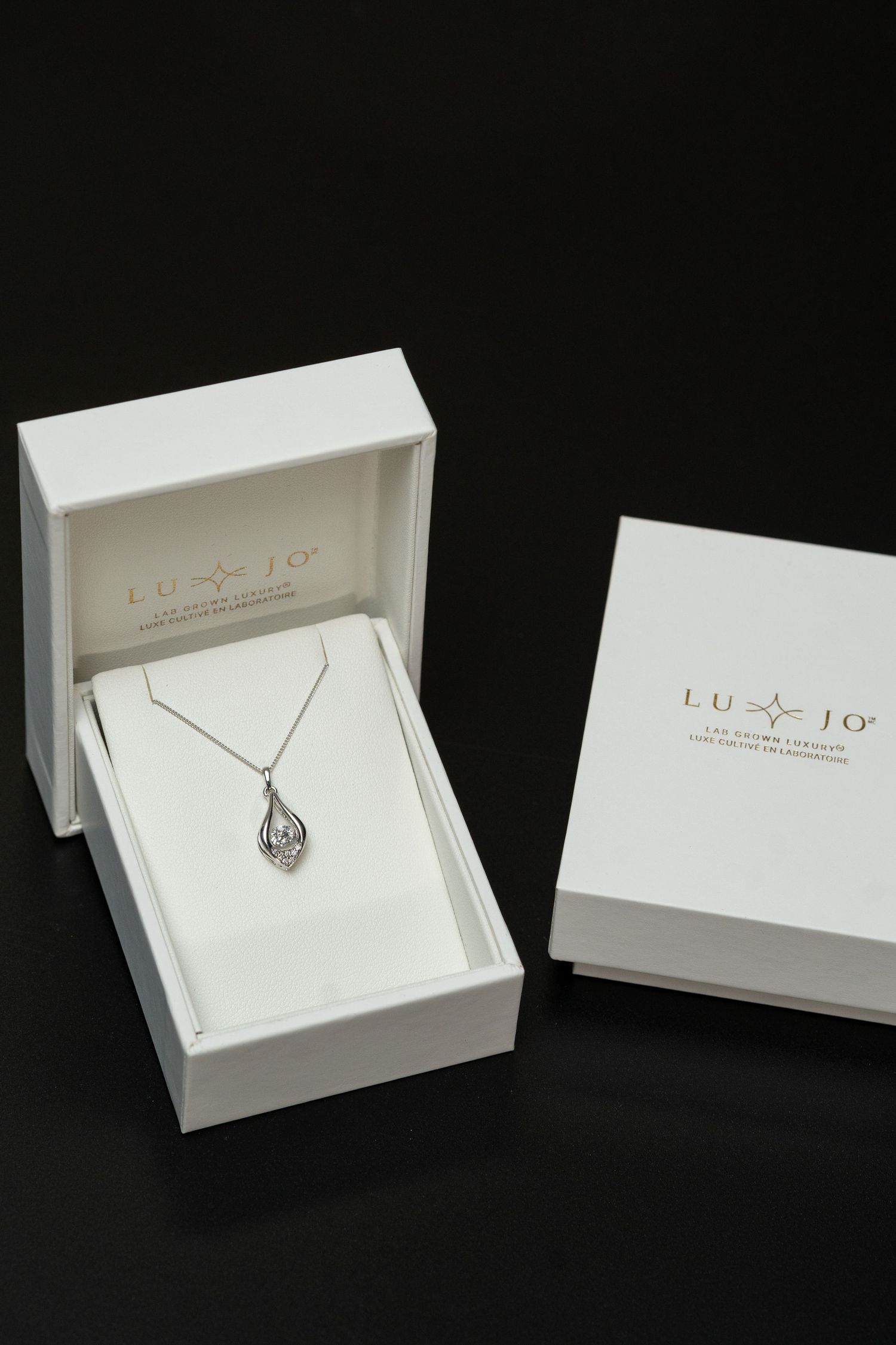 Luxury jewelry packaging boxes with heart-shaped pendant displayed inside.