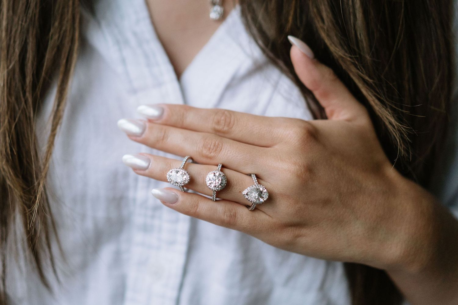 Detailed shots of diamond rings and jewelry displayed on hands with neutral background.