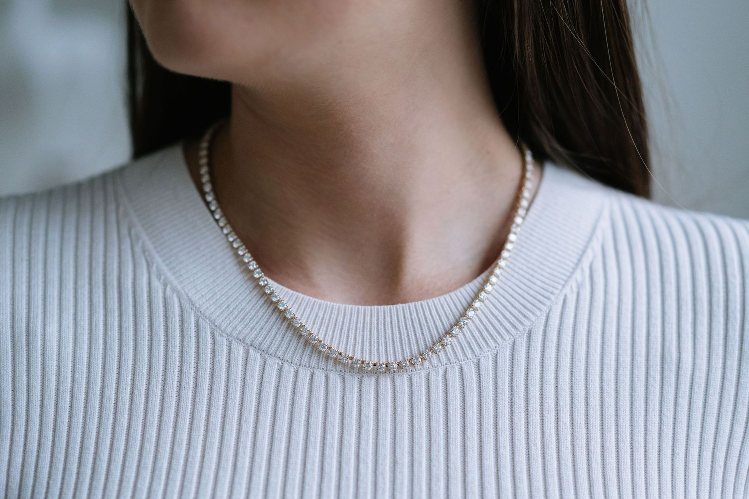 Person wearing a white sweater and delicate pearl necklace.