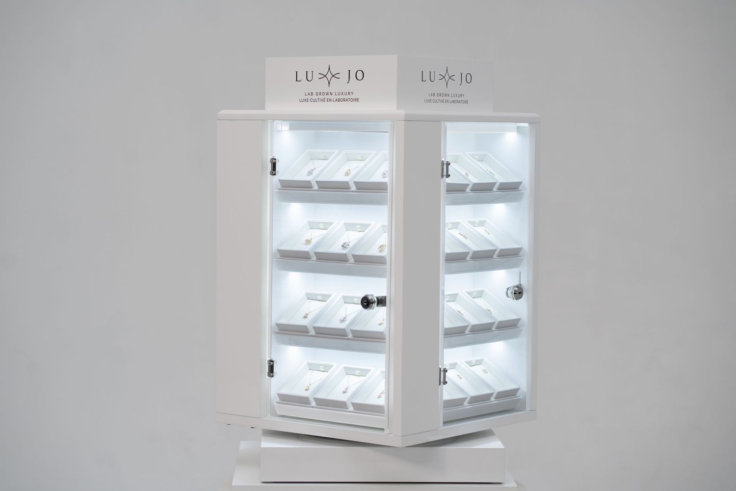 Elegant white jewelry display cases with brand logo arranged in a retail setting.
