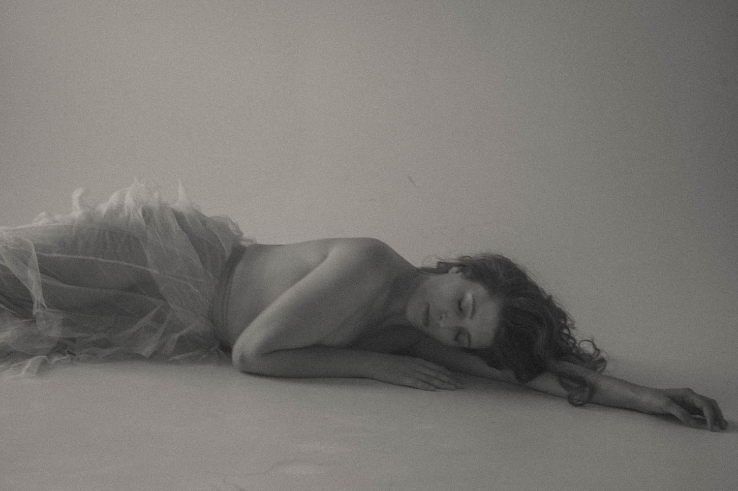 A black-and-white boudoir image showcasing elegant shadows and curves.