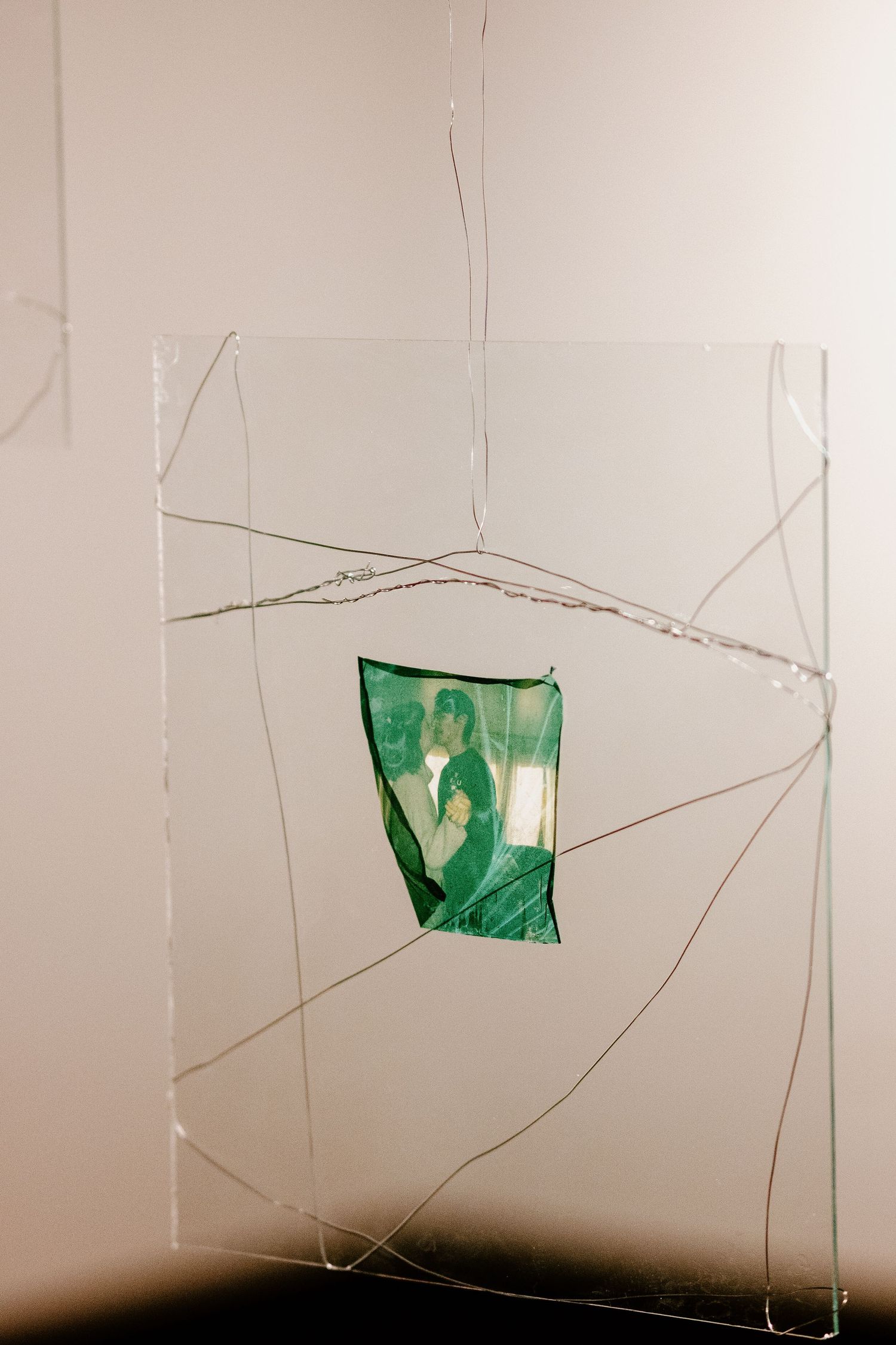 Minimalist art installation with green geometric shapes suspended on thin wires.