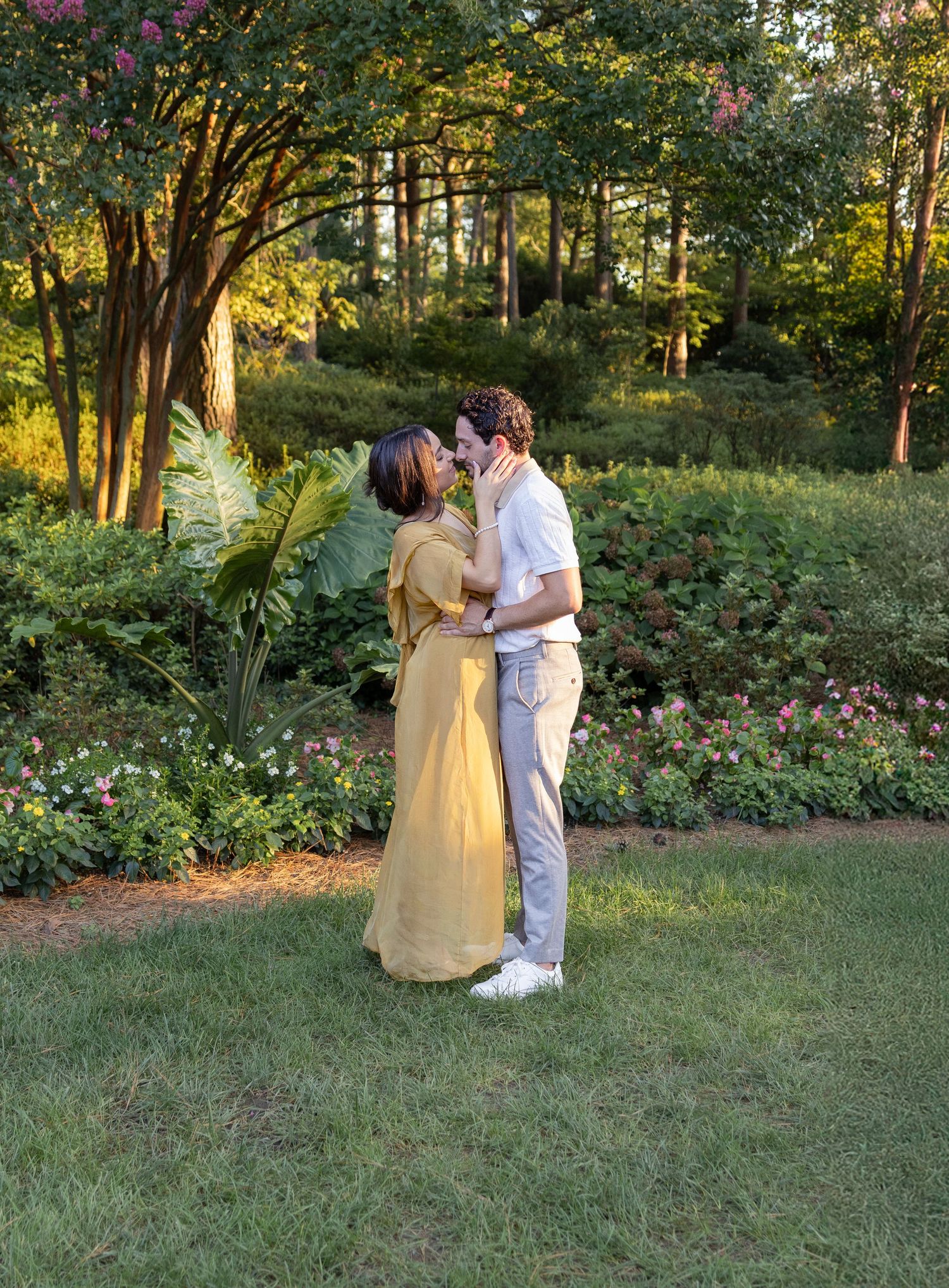 Romantic couple sharing an intimate moment in a lush garden setting at golden hour.