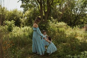 Dreamy garden scene with flowing blue dresses and natural summer light.