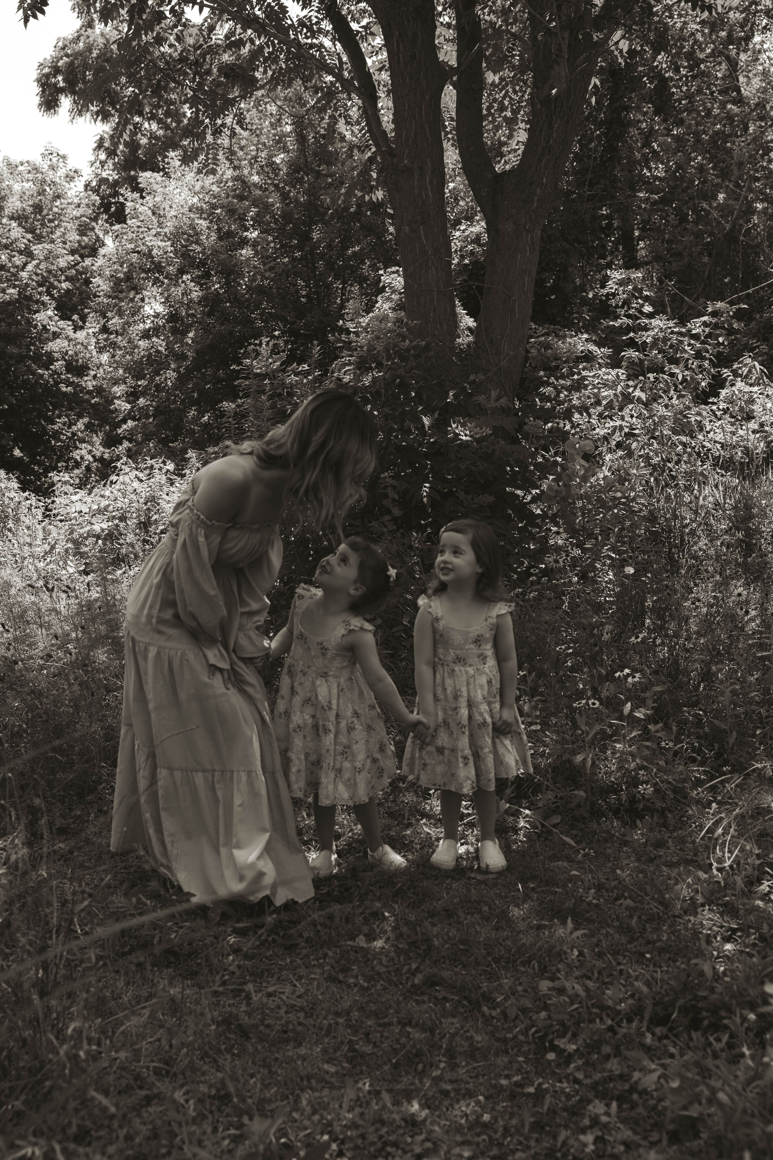 Vintage black and white photo of a tender outdoor family moment in a garden setting.