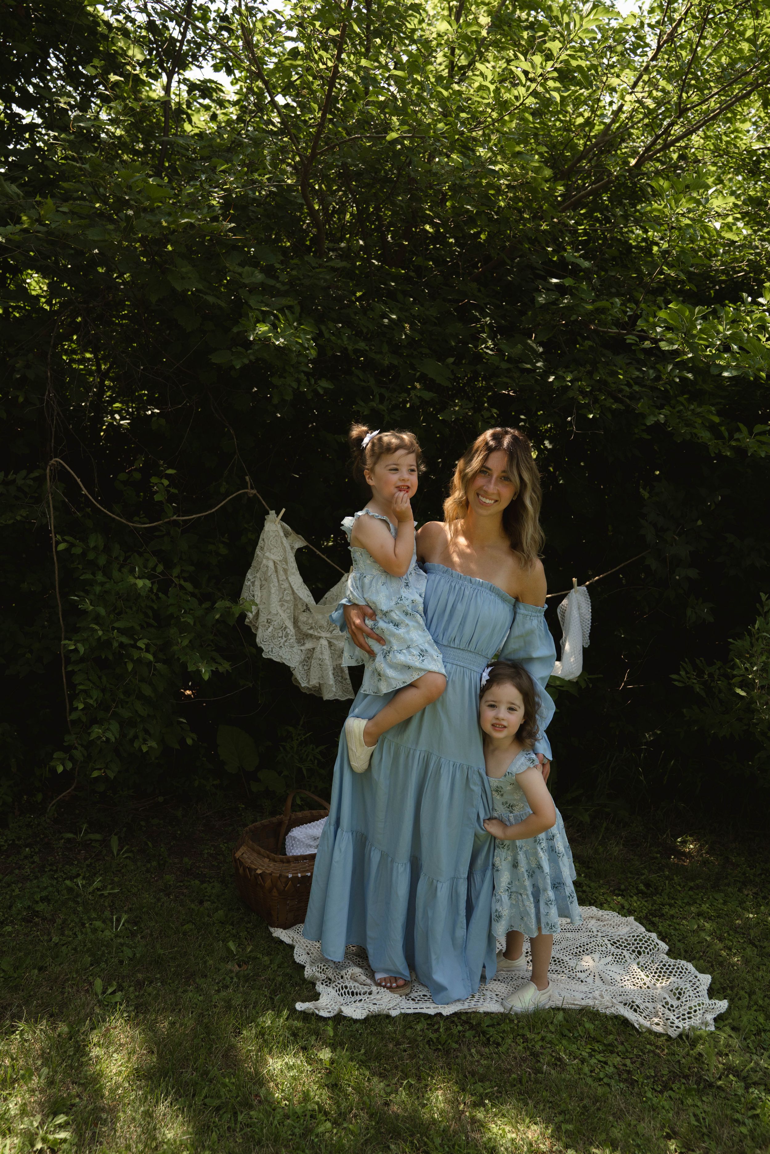 Family group in coordinating blue dresses posing in garden setting.