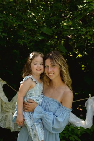 Intimate portrait against greenery with matching blue and floral dresses.