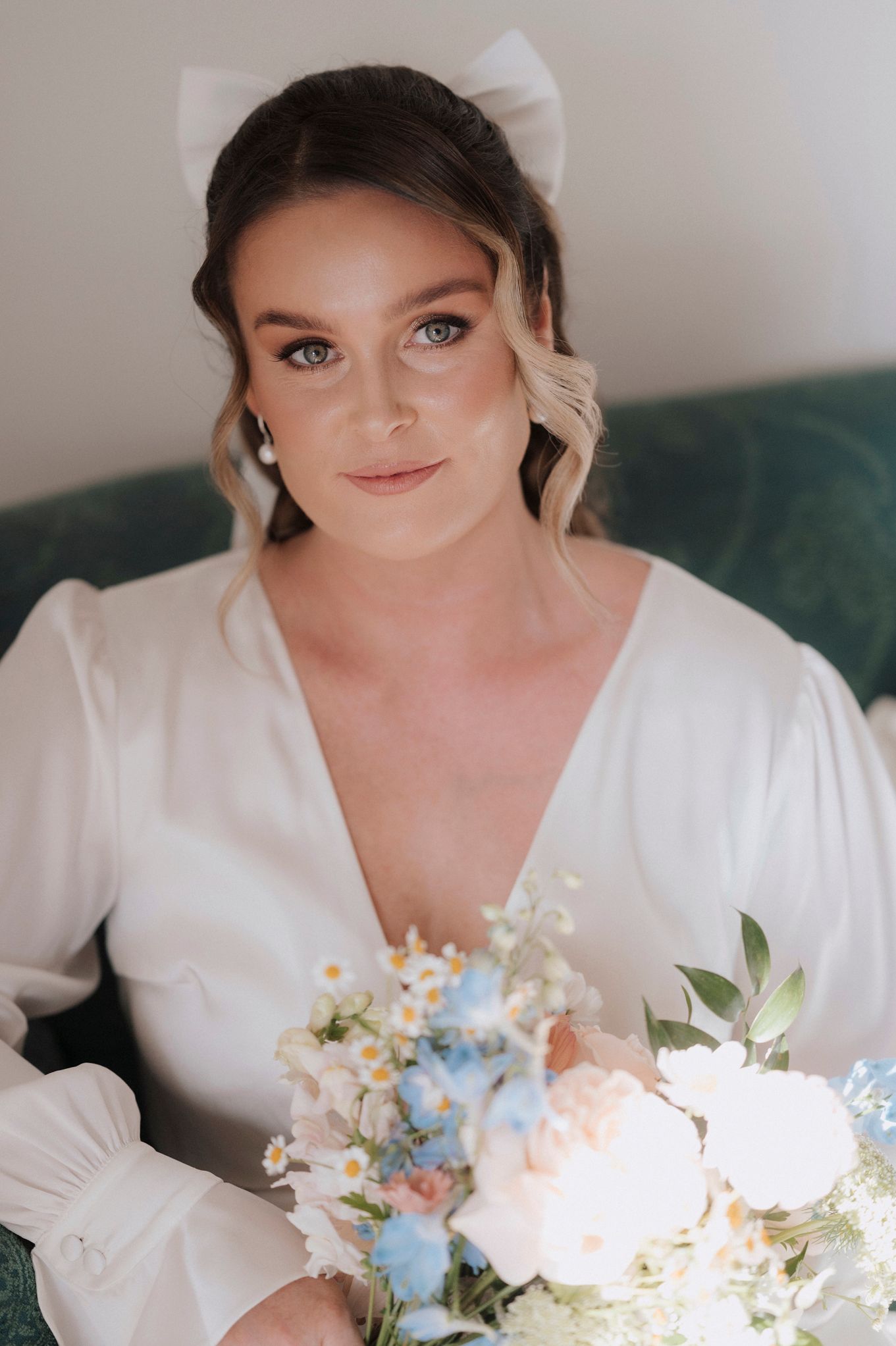 A person wearing white holds a soft pastel bouquet of flowers with pink and blue blooms.