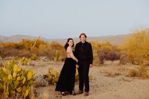 Desert landscape photoshoot with mountains and cacti in warm sunset lighting.