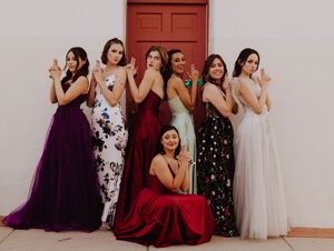 Prom Group photo of formal dresses in purple, white, and floral patterns against white wall.