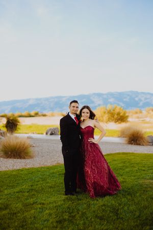 A formal couple's portrait on green grass with desert mountains in the background.