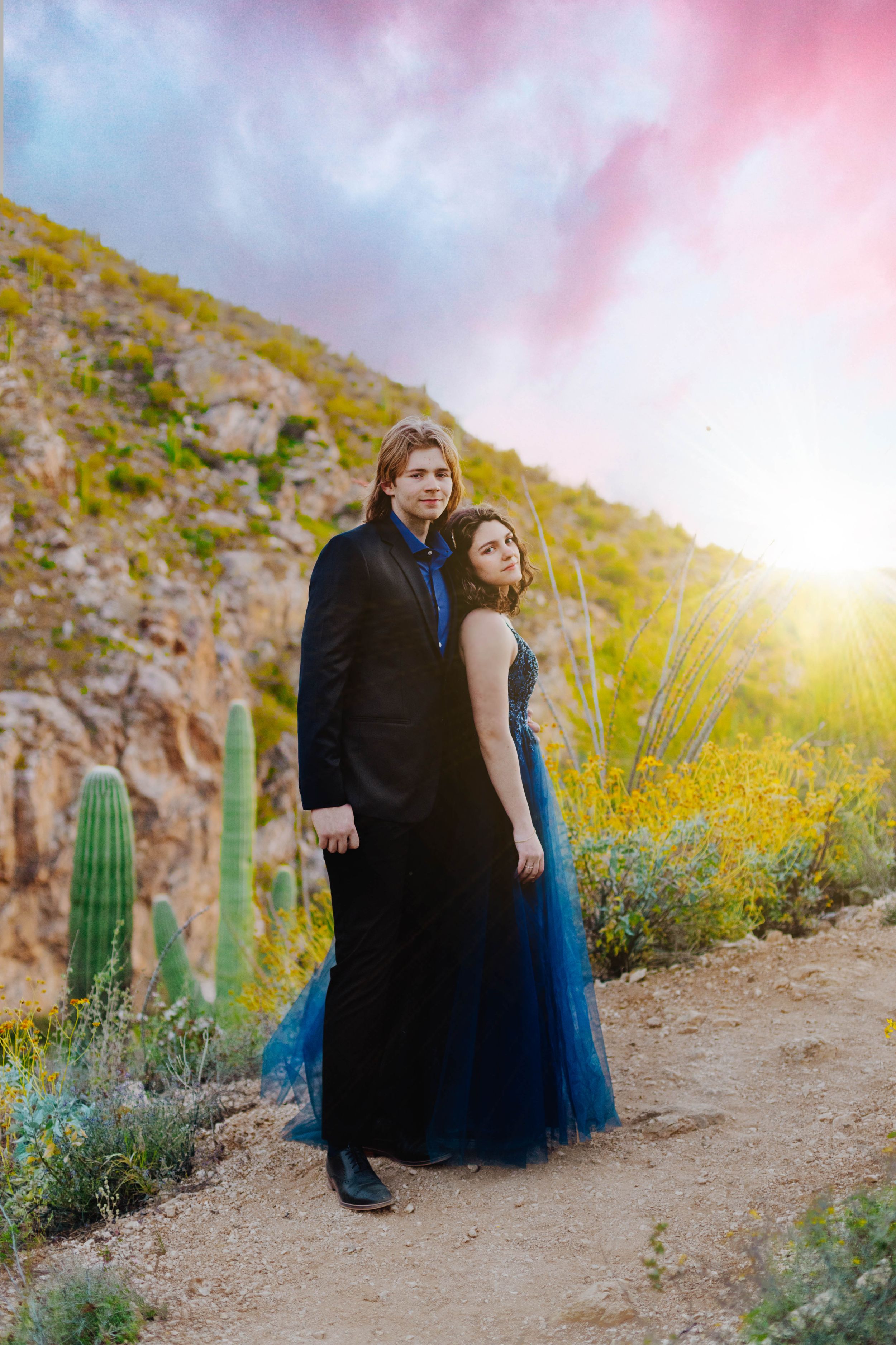 A desert photoshoot at sunset with cacti and mountain views in the background.