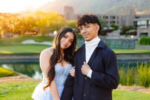 Formal couple poses together at sunset by a golf course lake at an elegant venue.