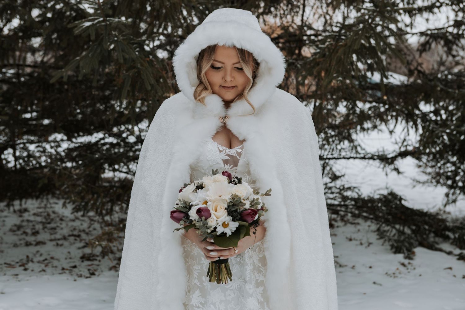 Winter bridal portraits in the snow featuring white fur cape and floral bouquet.