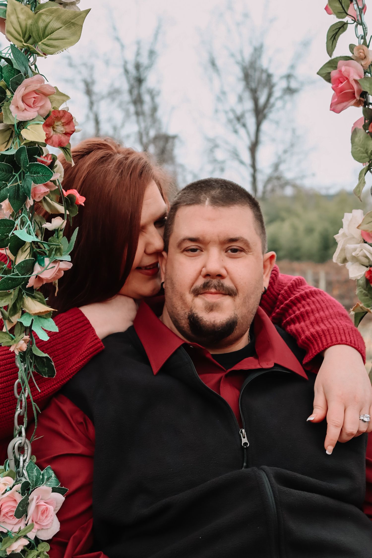 Romantic couple photography on a floral swing with pink and green decorative elements.