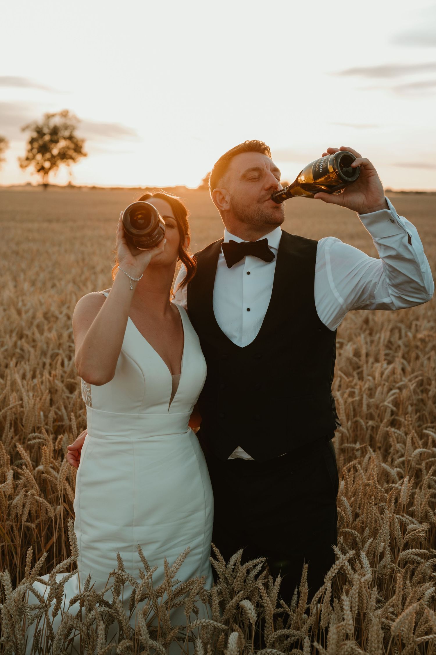 Romantic sunset portraits captured in a golden wheat field with dramatic backlighting.