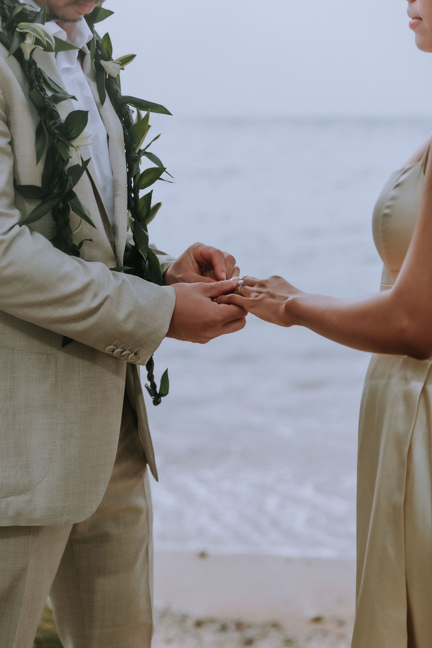 Close-up of couple exchanging rings during beach wedding ceremony.