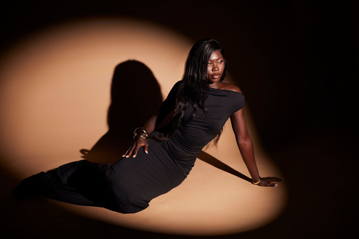 Dramatic boudoir photography series with warm spotlight creating artistic shadows.
