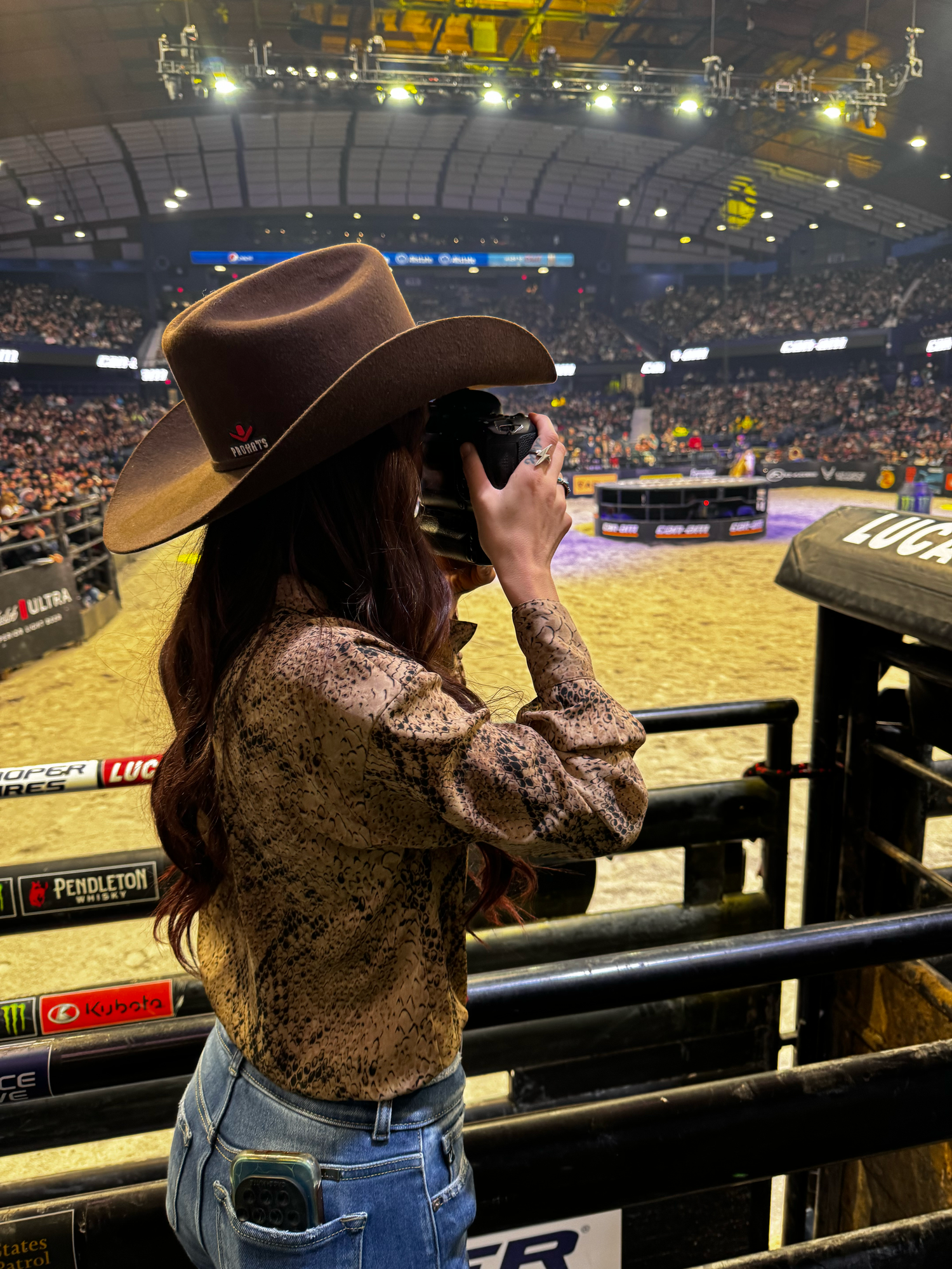 A sequence of cowboy hat silhouettes at a rodeo arena with bright stadium lighting and dirt floor visible in background.