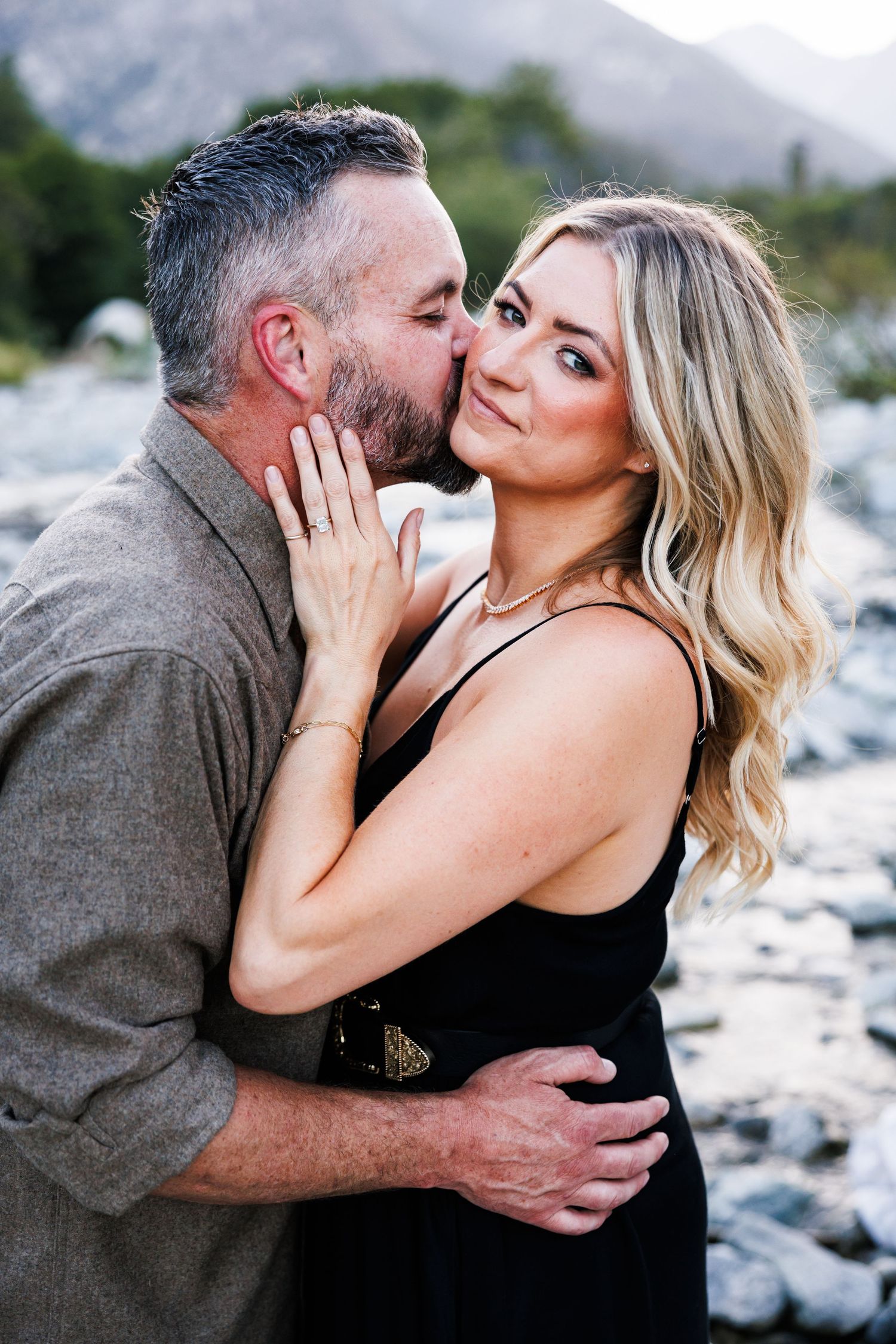 A romantic couple share passionate kisses on a rocky beach in a series of intimate black evening wear photos.