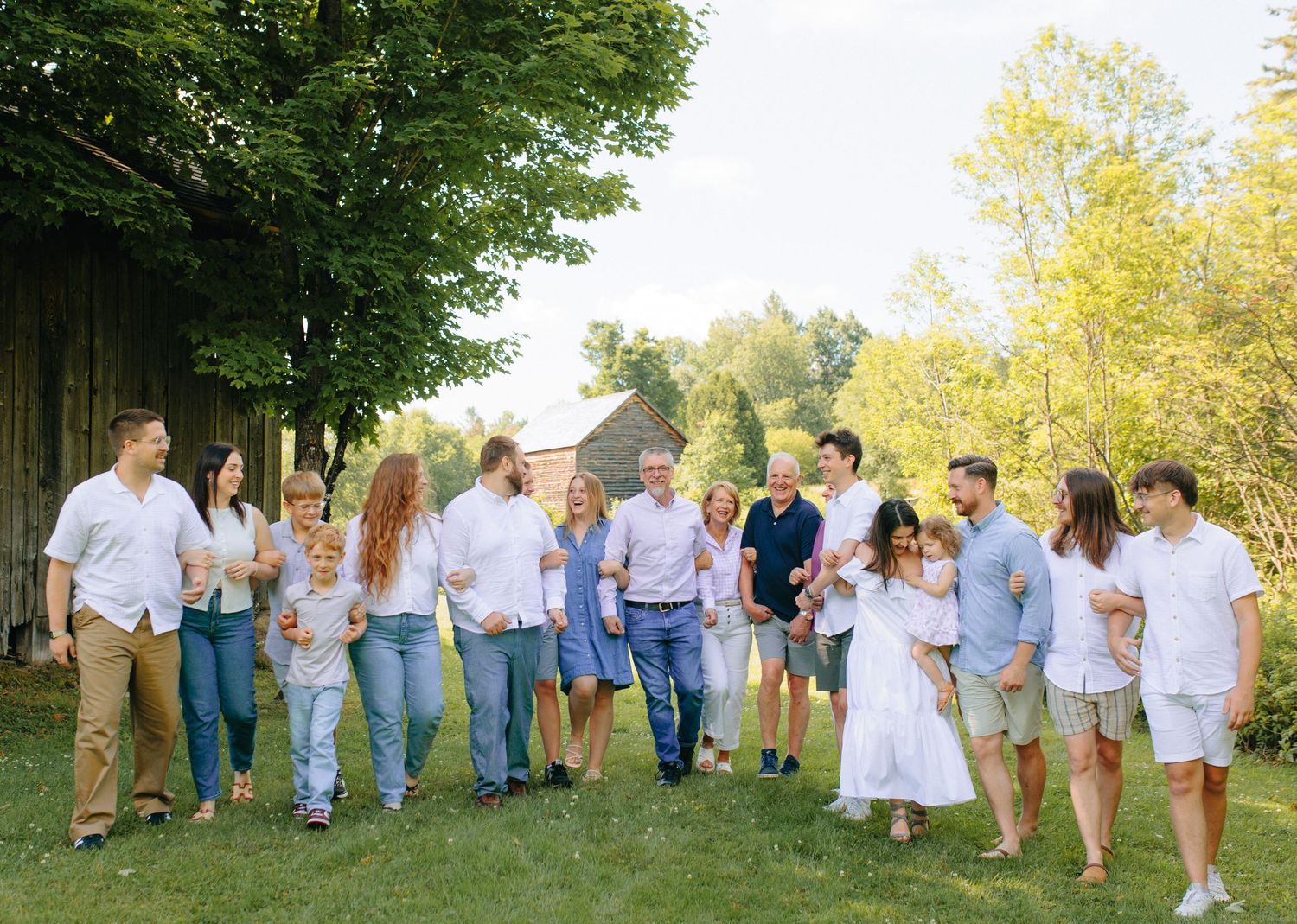 Large family group wearing coordinating blue and white outfits poses together at outdoor photoshoot.