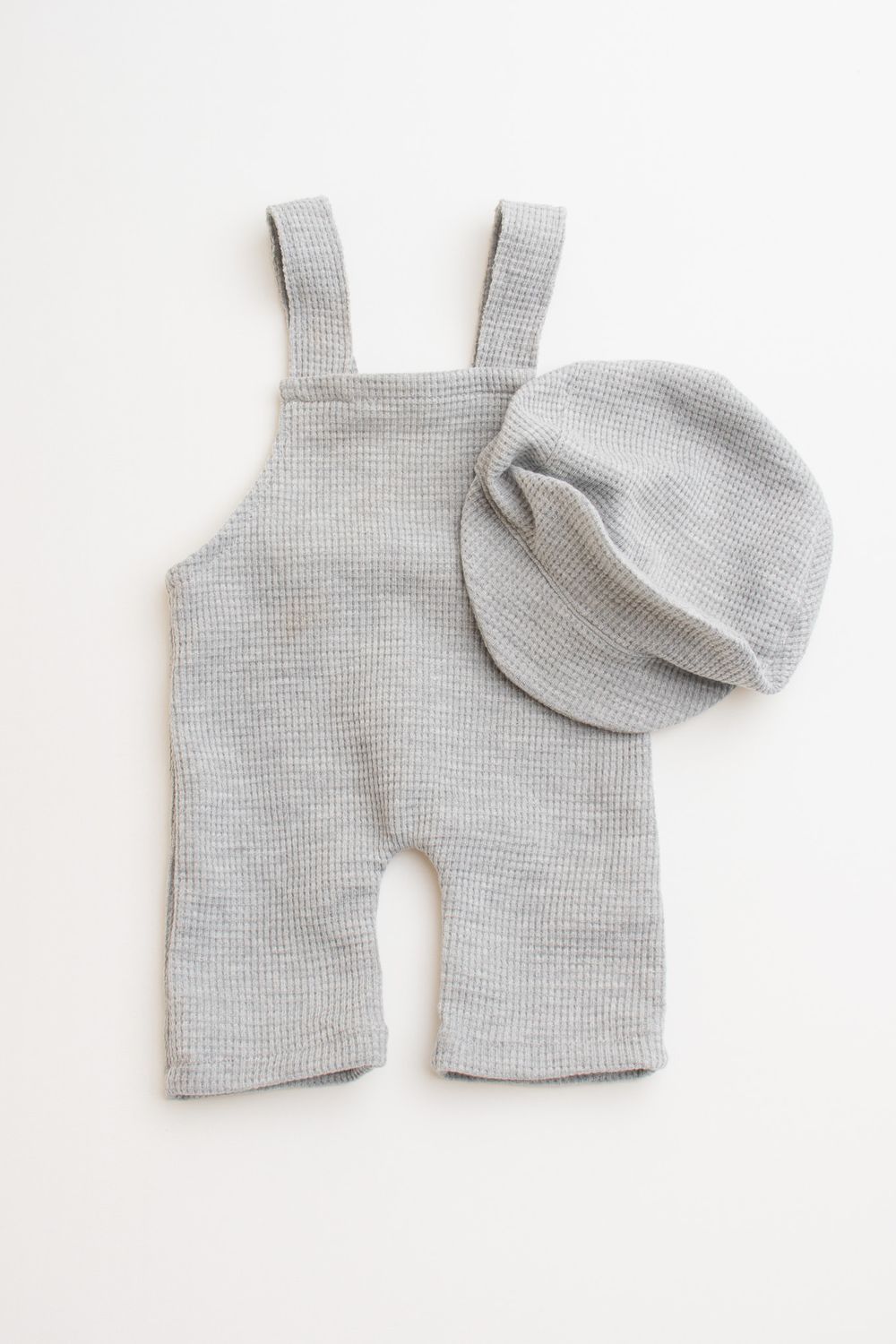 Gray knit baby overalls and matching beanie hat set displayed on white background.