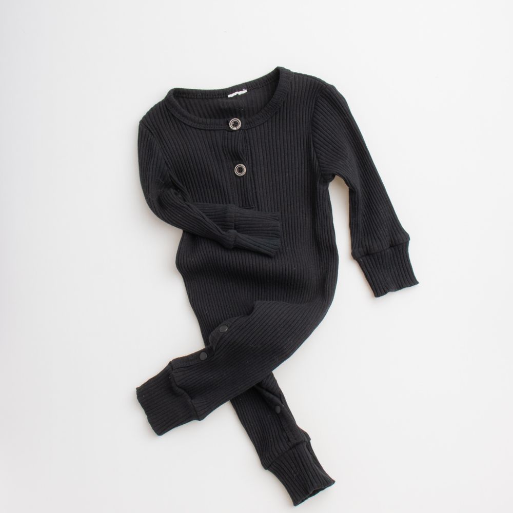 Black ribbed knit baby romper with long sleeves and button details laid flat on white background.