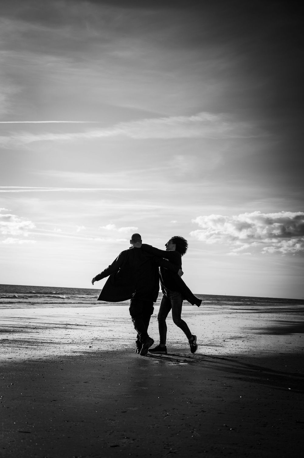 Schwarz-Weiß-Silhouette eines tanzenden Paares am Strand in Dänemark bei Sonnenuntergang – poetisch, ruhig, voller Gefühl.
