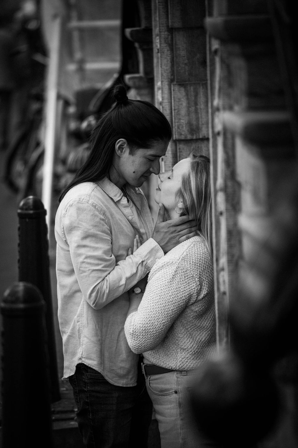 Schwarz-Weiß-Foto eines Paares in Amsterdam am Hauseingang, das sich tief in die Augen blickt, während er ihr Gesicht hält.