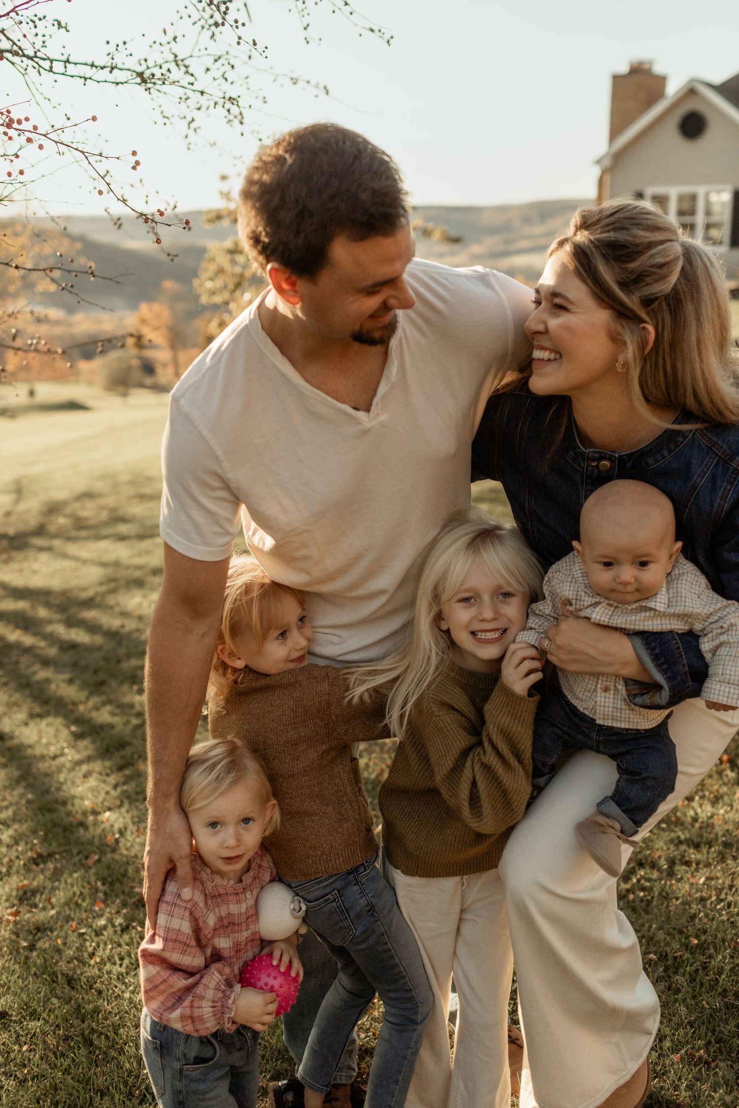 Couple sharing a joyful embrace during golden hour in casual fall attire.