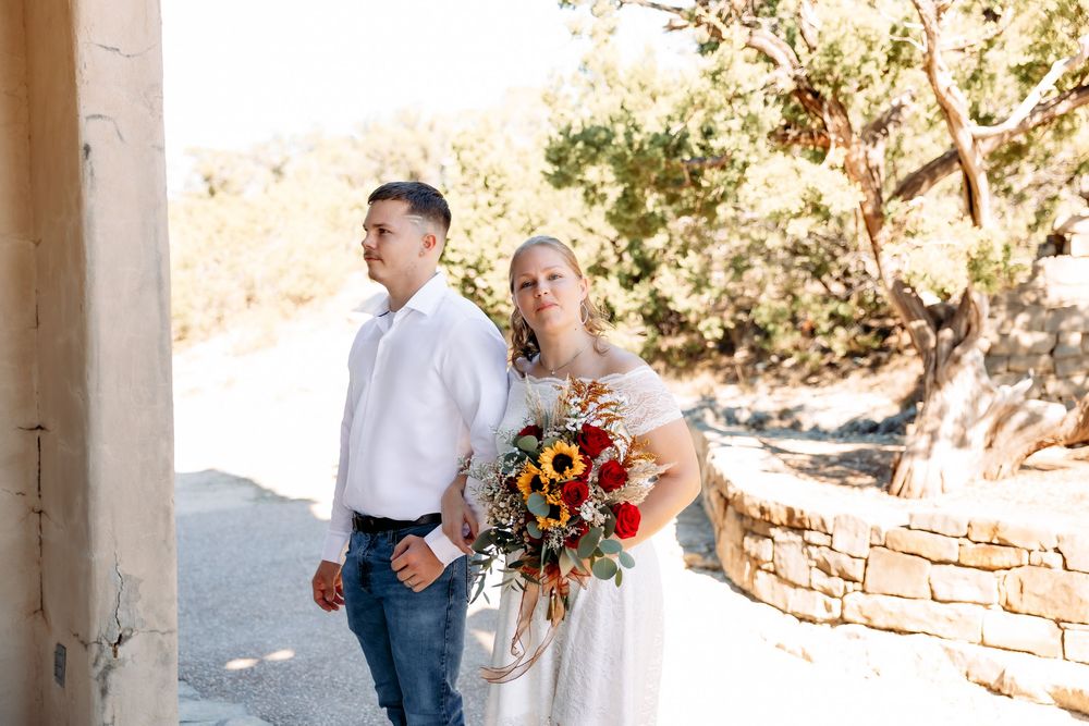 Couple sharing intimate moments during engagement photoshoot in rustic outdoor setting with stone walls and natural light.
