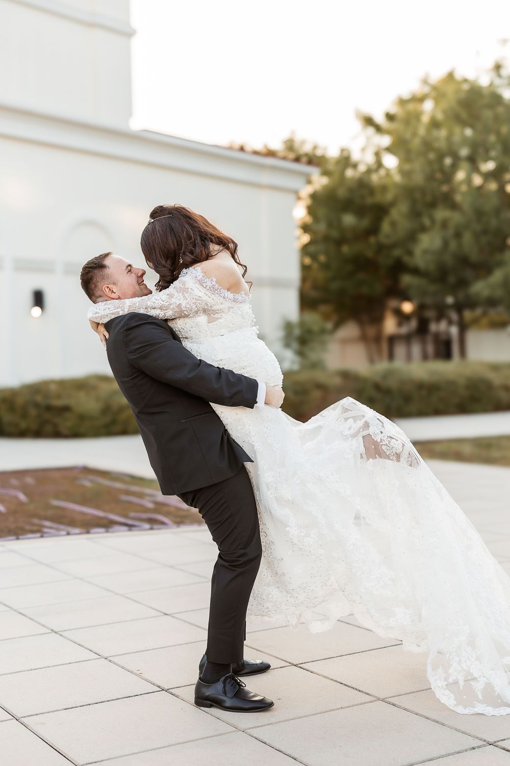 A romantic wedding sequence shows a groom lifting and spinning the bride in her flowing white lace gown on a paved terrace.
