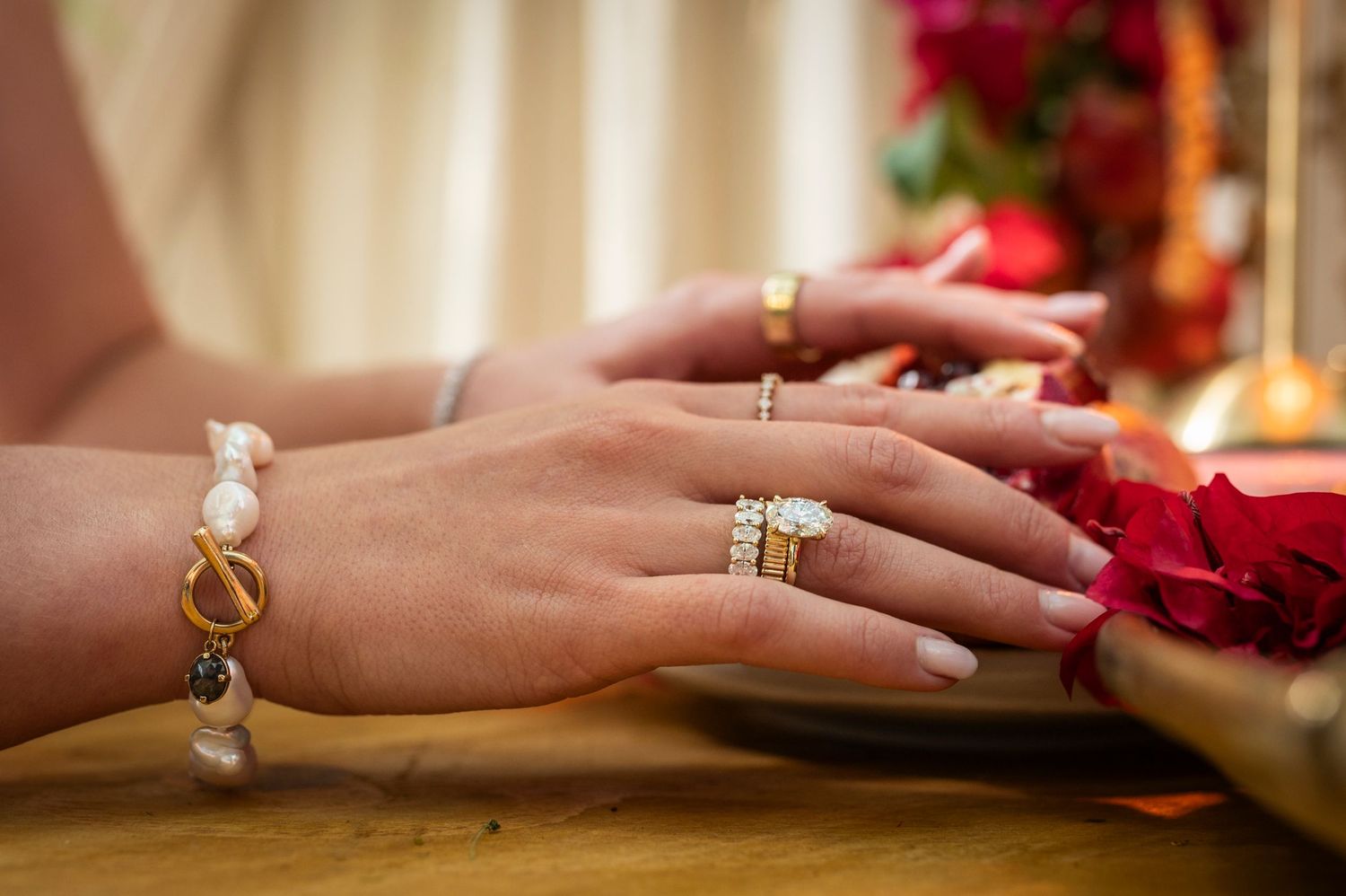 Several gold and silver rings adorned with black stones and diamonds displayed on hands with pale pink manicured nails.