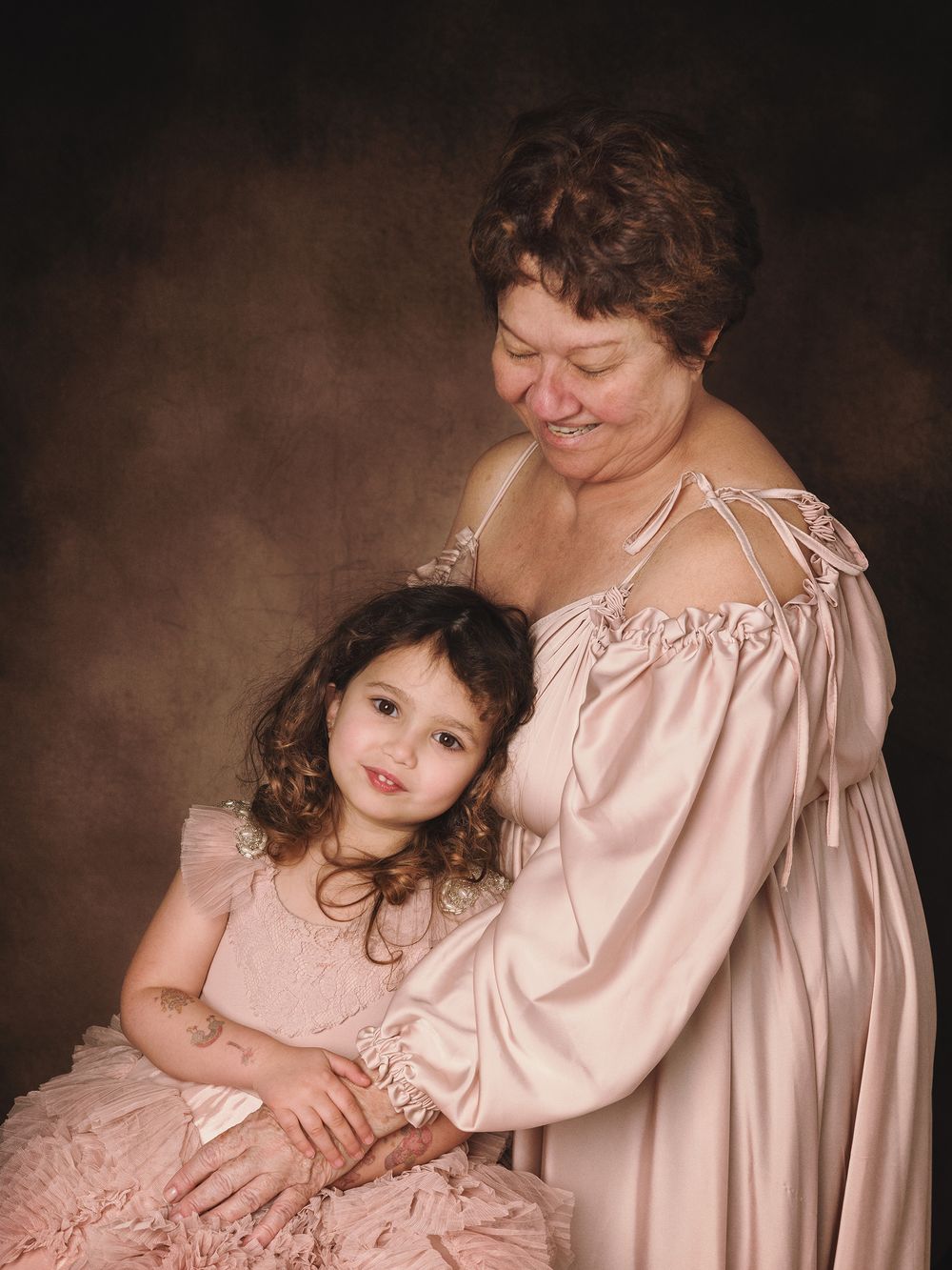 A tender portrait series in warm pink and brown tones shows intimate moments of connection and embrace in a studio setting.